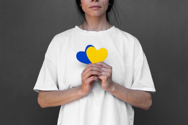 Женщина вид спереди держит желтые и синие сердца