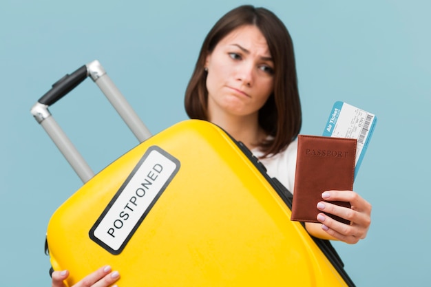 Женщина вид спереди держит желтый багаж с отложенным знаком