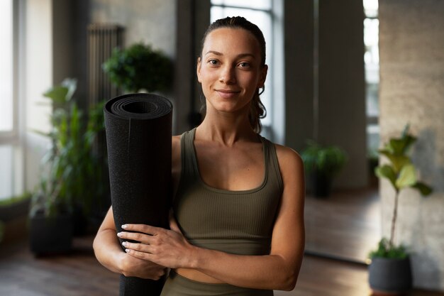 Front view woman holding yoga mat