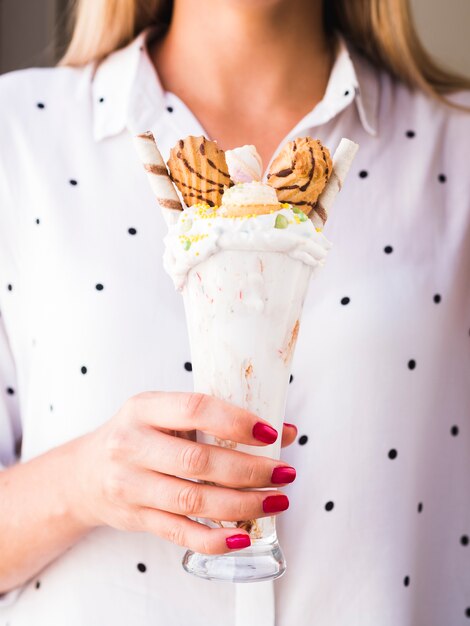 Front view of a woman holing a glass of milkshake