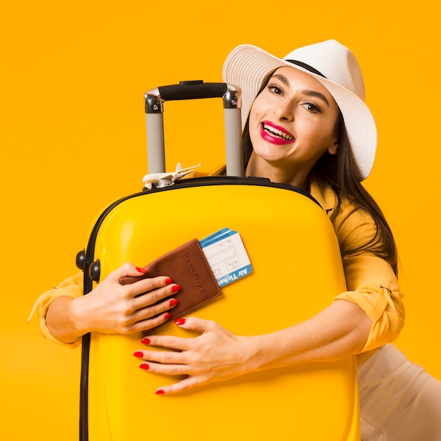 Вид спереди женщины обнимает багаж и держит паспорт с билетами на самолет