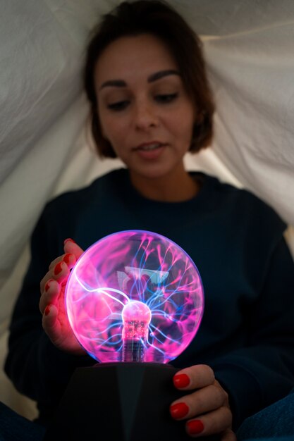 Front view woman interacting with a plasma ball