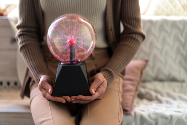 Front view woman interacting with a plasma ball