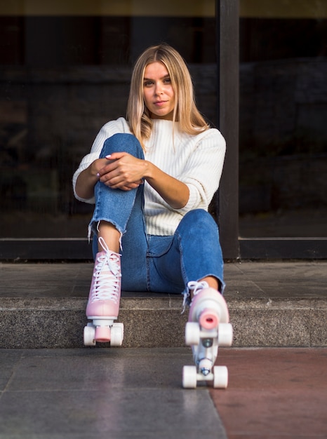 Free photo front view of woman in jeans posing with roller skates