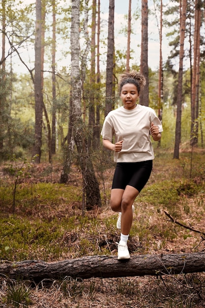 Front view woman jumping over log