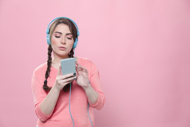 front view of woman listening to music on headphones while holding smartphone