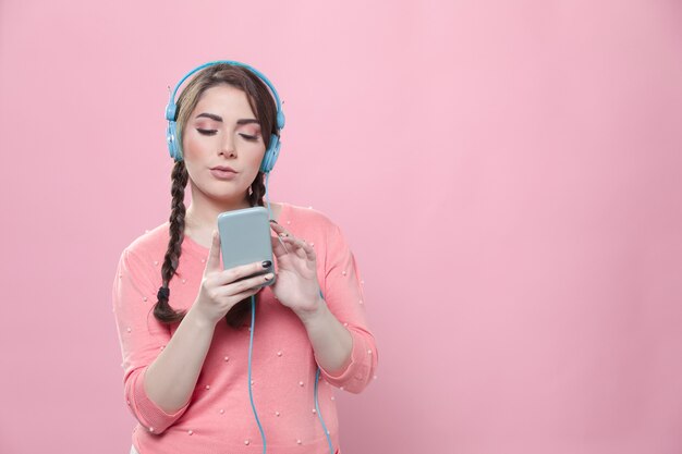 スマートフォンを押しながらヘッドフォンで音楽を聴く女性の正面図