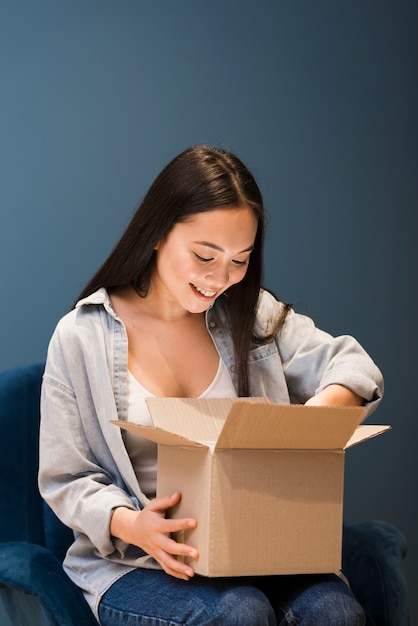 Front view of woman looking in box after ordering online