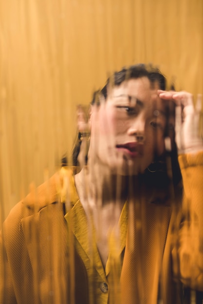 front view woman looking at the camera behind wet glass