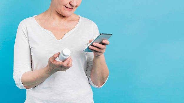 스마트 폰을 사용하여 인터넷에서 그녀의 약을 찾는 여자의 전면보기