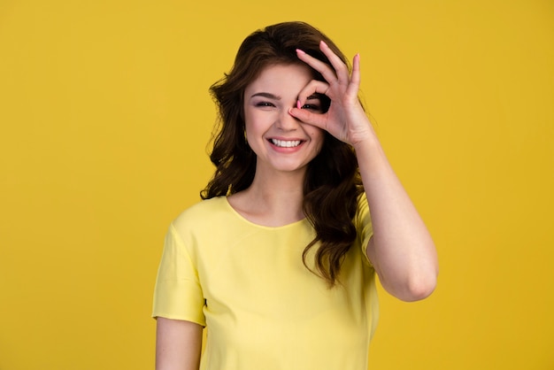 Front view of woman making the ok sign over her eye