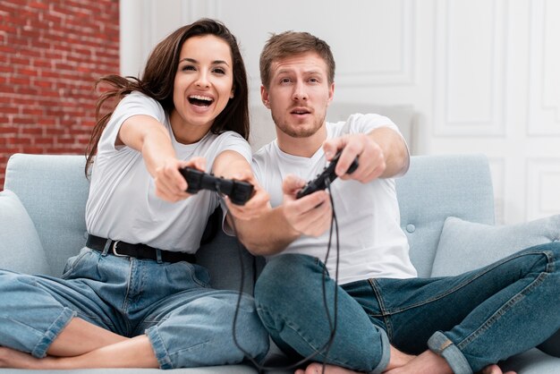 Front view woman and man having fun while playing with controllers