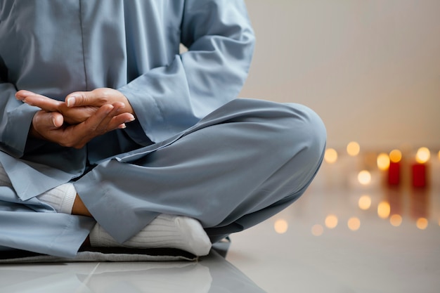 Front view of woman meditating next to candles