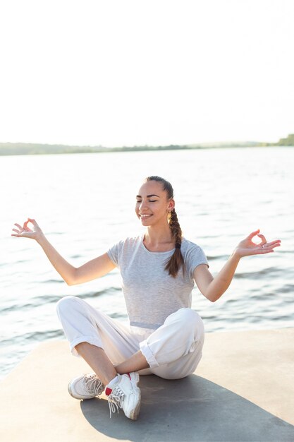 Front view woman meditating on dock