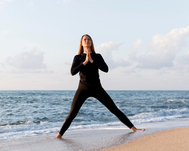 Front view woman meditating on sand