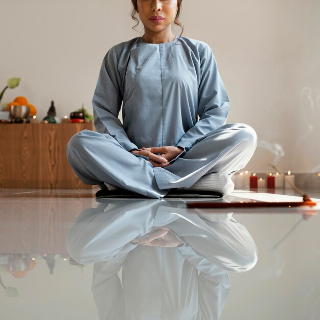 Front view of woman meditating with incense