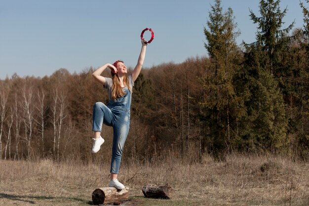 Front view of woman in nature holding tambourine