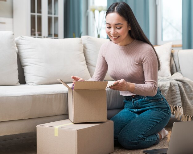 Front view of woman opening boxes after ordering online