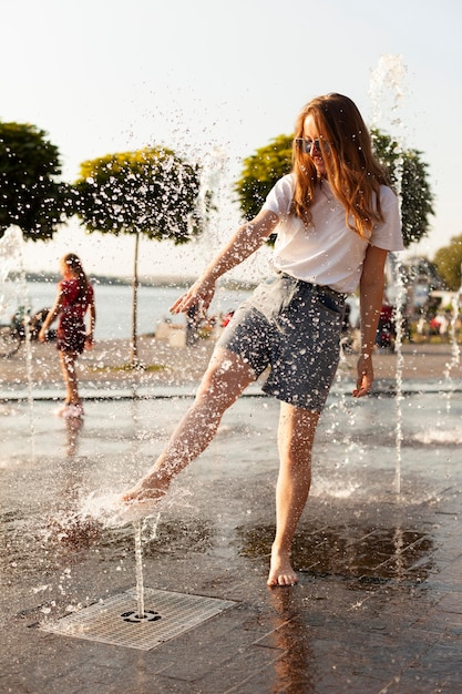 Вид спереди женщины на открытом воздухе весело у фонтана