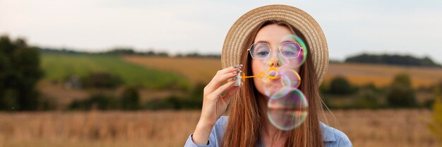 Front view of woman outdoors making soap bubbles