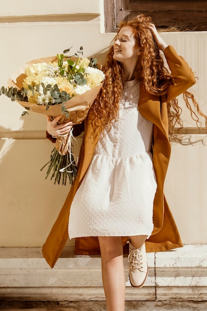 Free photo front view of woman outdoors with bouquet of spring flowers