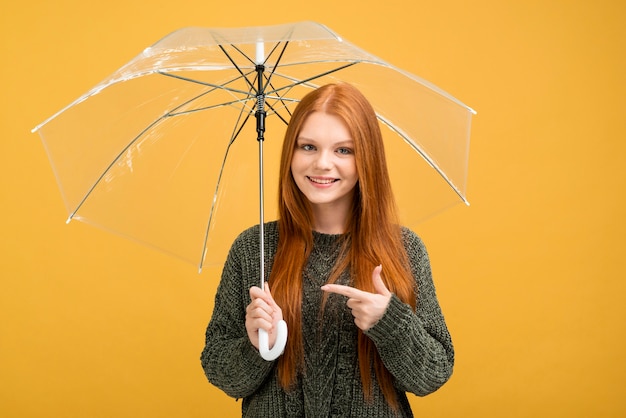 Foto gratuita donna di vista frontale che indica all'ombrello