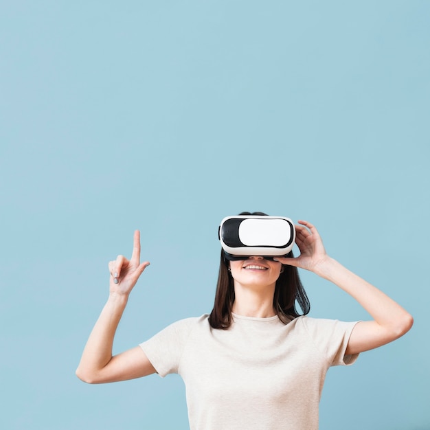 Вид спереди женщины, указывая во время ношения гарнитуры виртуальной реальности