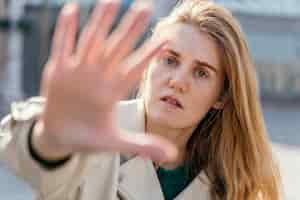 Free photo front view of woman posing outdoors in the city and reaching her hand