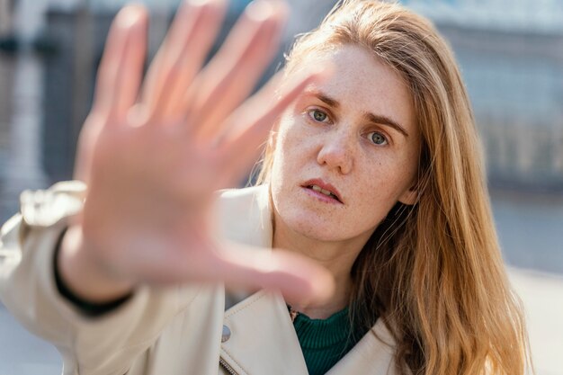 Front view of woman posing outdoors in the city and reaching her hand