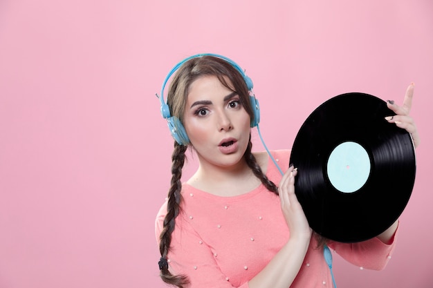 Front view of woman posing shocked with vinyl record and copy space