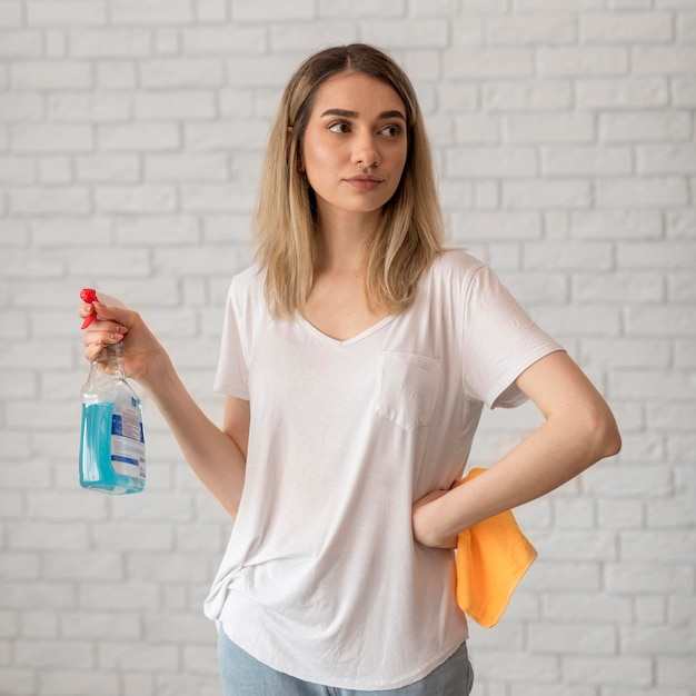 Front view of woman posing while holding cleaning solution and cloth