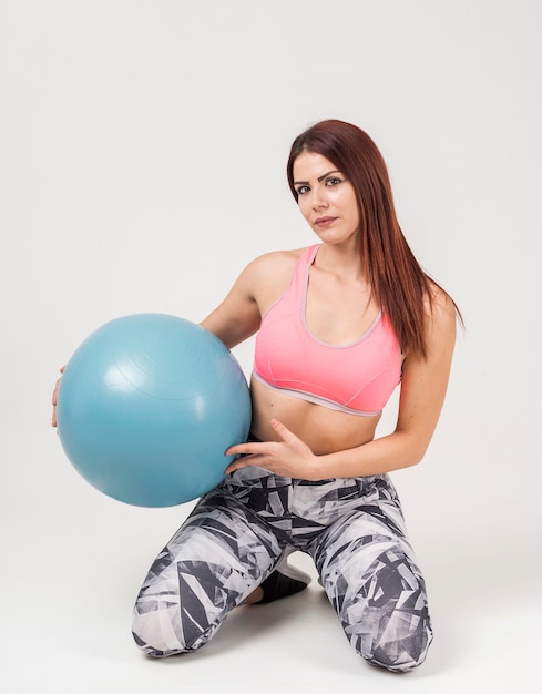 Front view of woman posing while holding exercise ball