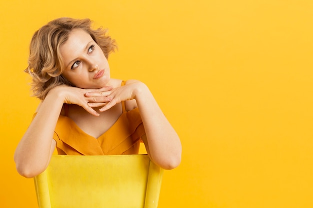 Free photo front view of woman posing while sitting on chair