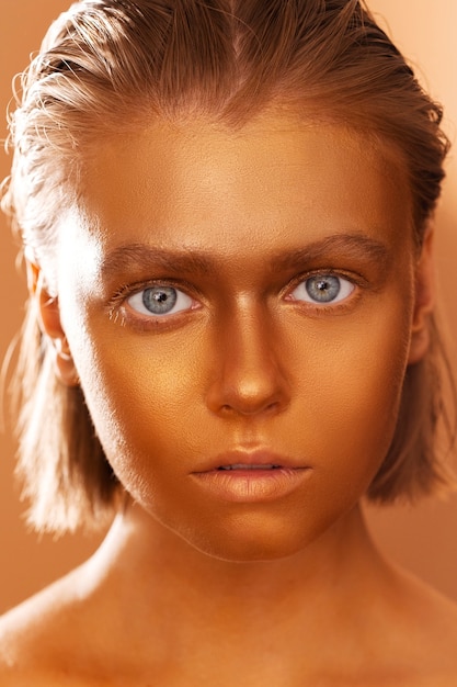 Foto gratuita donna di vista frontale che posa con la pittura del corpo dell'oro