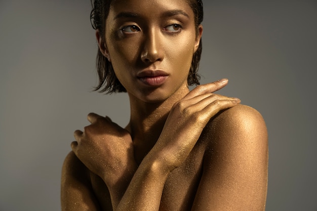 Front view woman posing with gold body painting