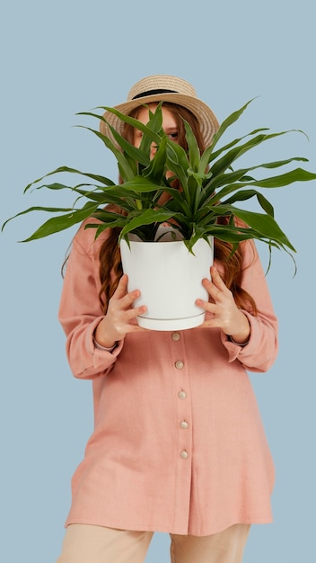 Free photo front view of woman posing with pot of plant