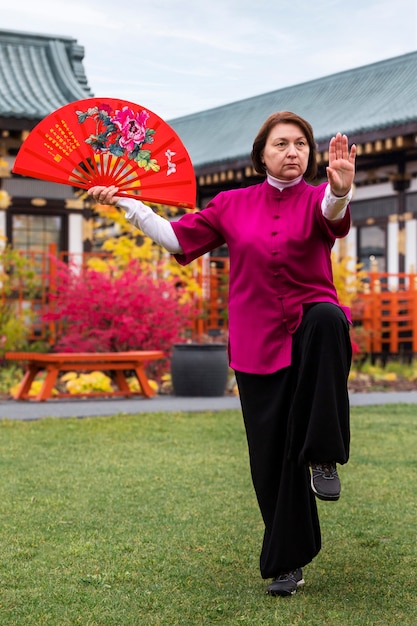 Foto gratuita donna di vista frontale che pratica il tai chi all'aperto