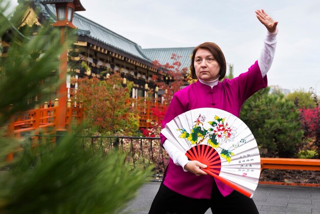 Front view woman practicing tai chi with fan