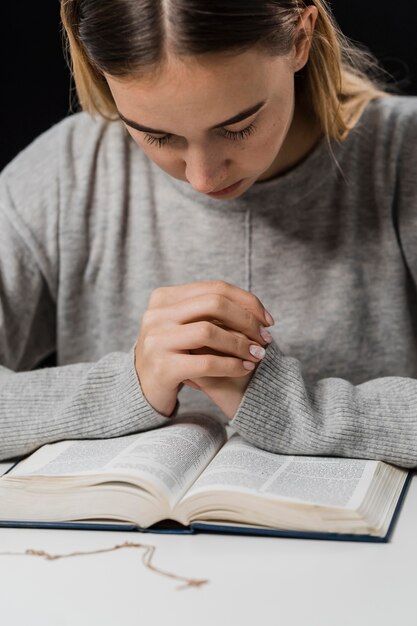 Front view of woman praying and reading from the bible