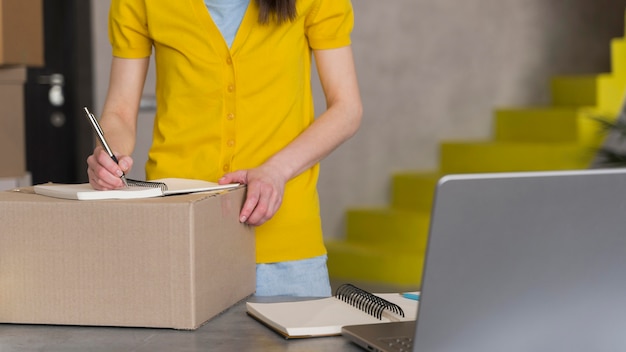 Free photo front view of woman preparing box for shipment with laptop