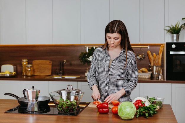 Vista frontale della donna che prepara il cibo in cucina a casa