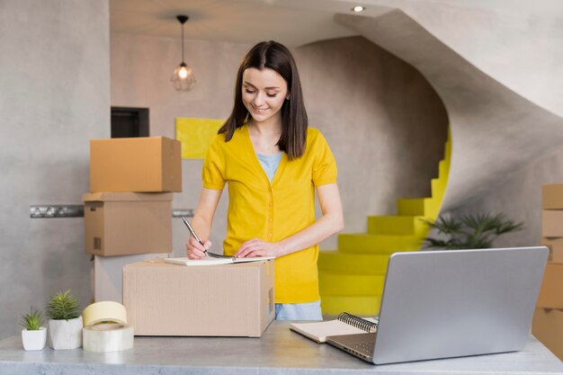 Front view of woman preparing orders in boxes to ship