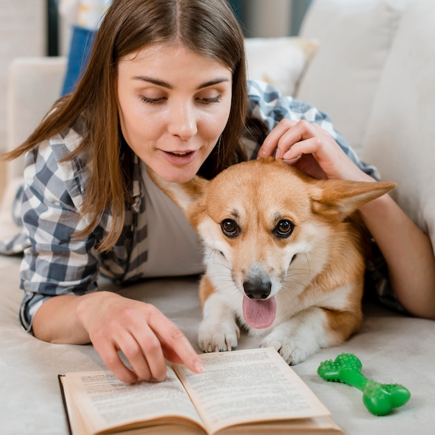 ソファの上の犬と一緒に本を読む女性の正面図