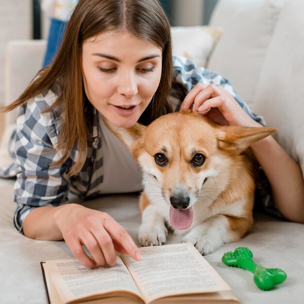 ソファの上の犬と一緒に本を読む女性の正面図