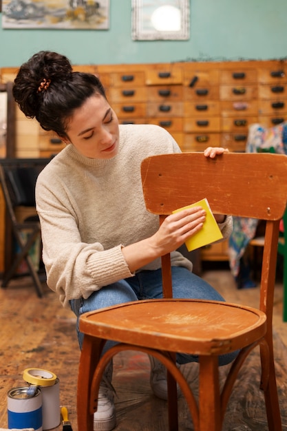 Женщина вид спереди восстанавливает деревянный стул дома