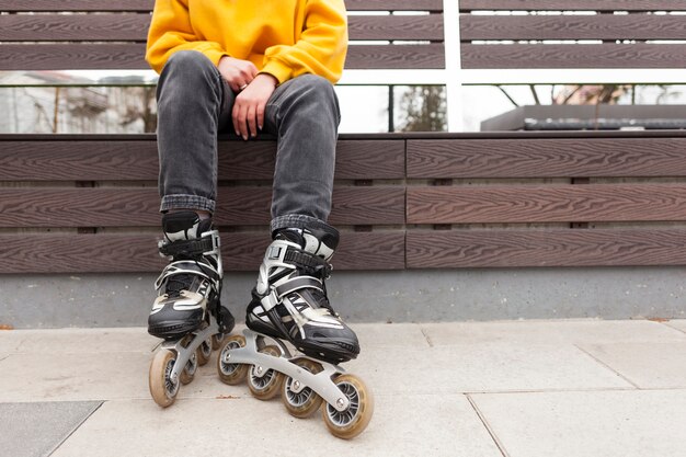 Front view of woman in roller blades sitting on bench