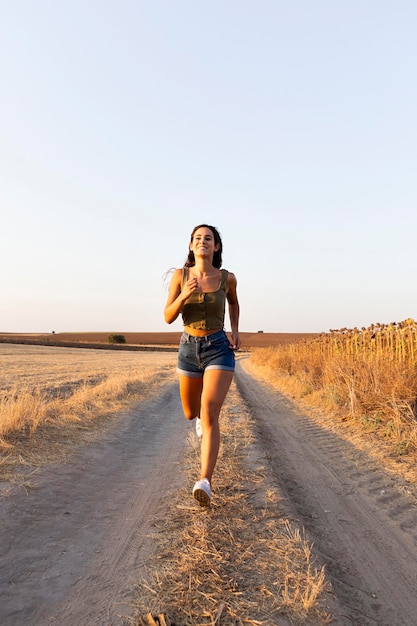 Free photo front view of woman running on road in nature with copy space