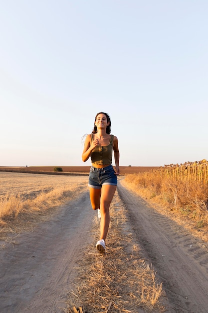 Вид спереди женщины, бегущей по дороге в природе с копией пространства