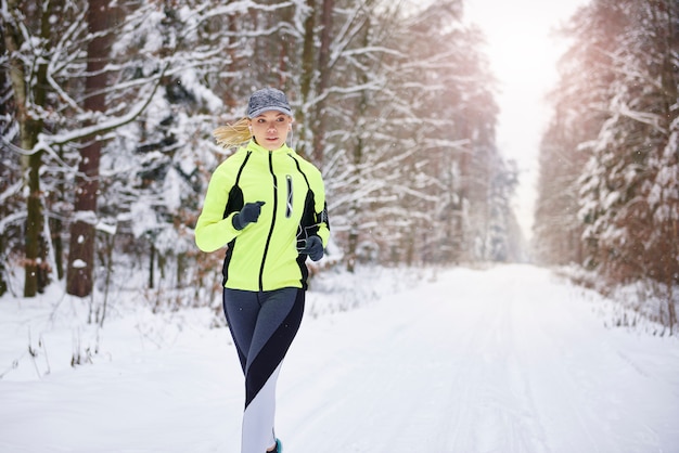 Foto gratuita vista frontale della donna che corre nella foresta invernale