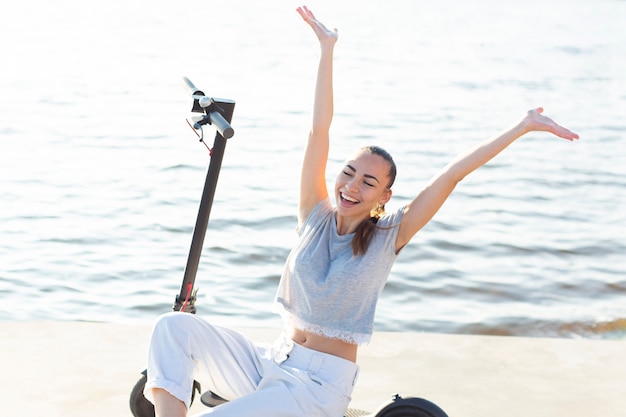 Foto gratuita donna di vista frontale che mostra felicità seduto su uno scooter